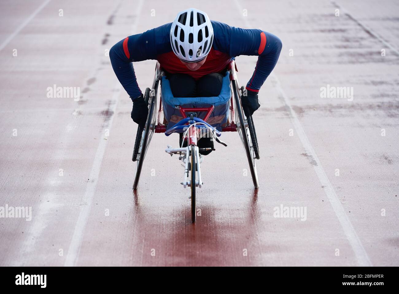 Preparazione per la maratona su sedia a rotelle. Vista ravvicinata della velocità di allenamento paraplegica degli atleti maschi mentre gareggiano su una sedia a rotelle sportiva su un tracciato all'aperto Foto Stock