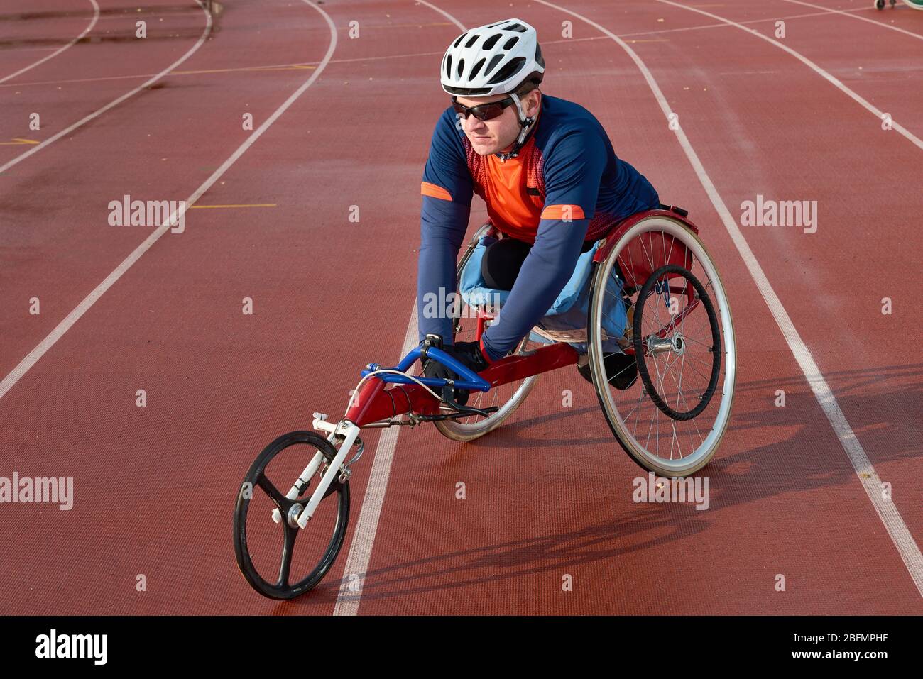 Prepararsi per la maratona. Sportivo paraplegico professionista in carrozzina da corsa che si riscalda prima della competizione in pista e stadio di campo Foto Stock