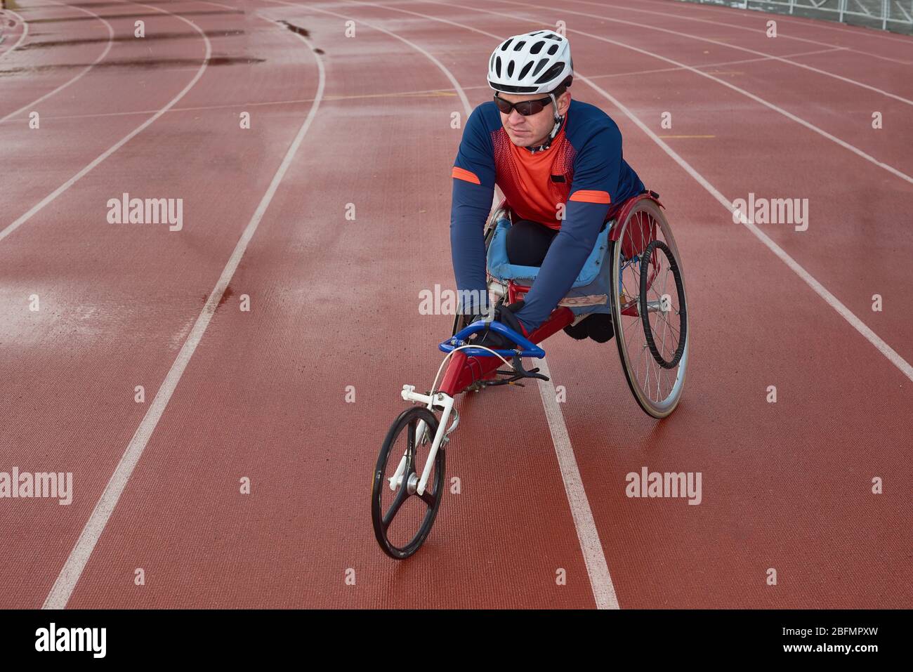 Futuro campione Paralimpico. Paraplegico atleta maschile seduto su sedia a rotelle specializzata e si riscalda in pista prima della gara Foto Stock