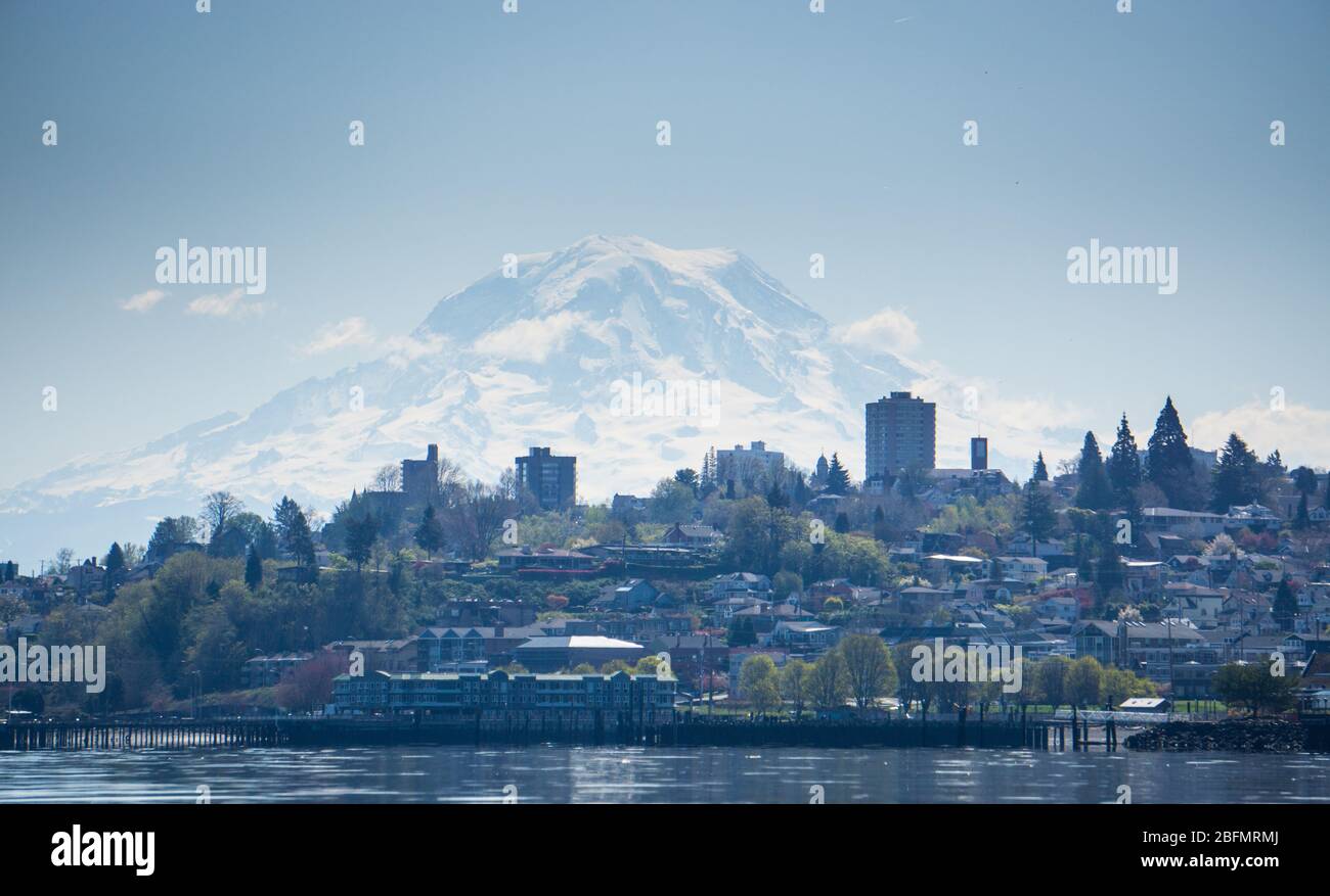 Mt. Rainier splende attraverso la foschia atmosferica sopra lo skyline di Tacoma, WA. Foto Stock