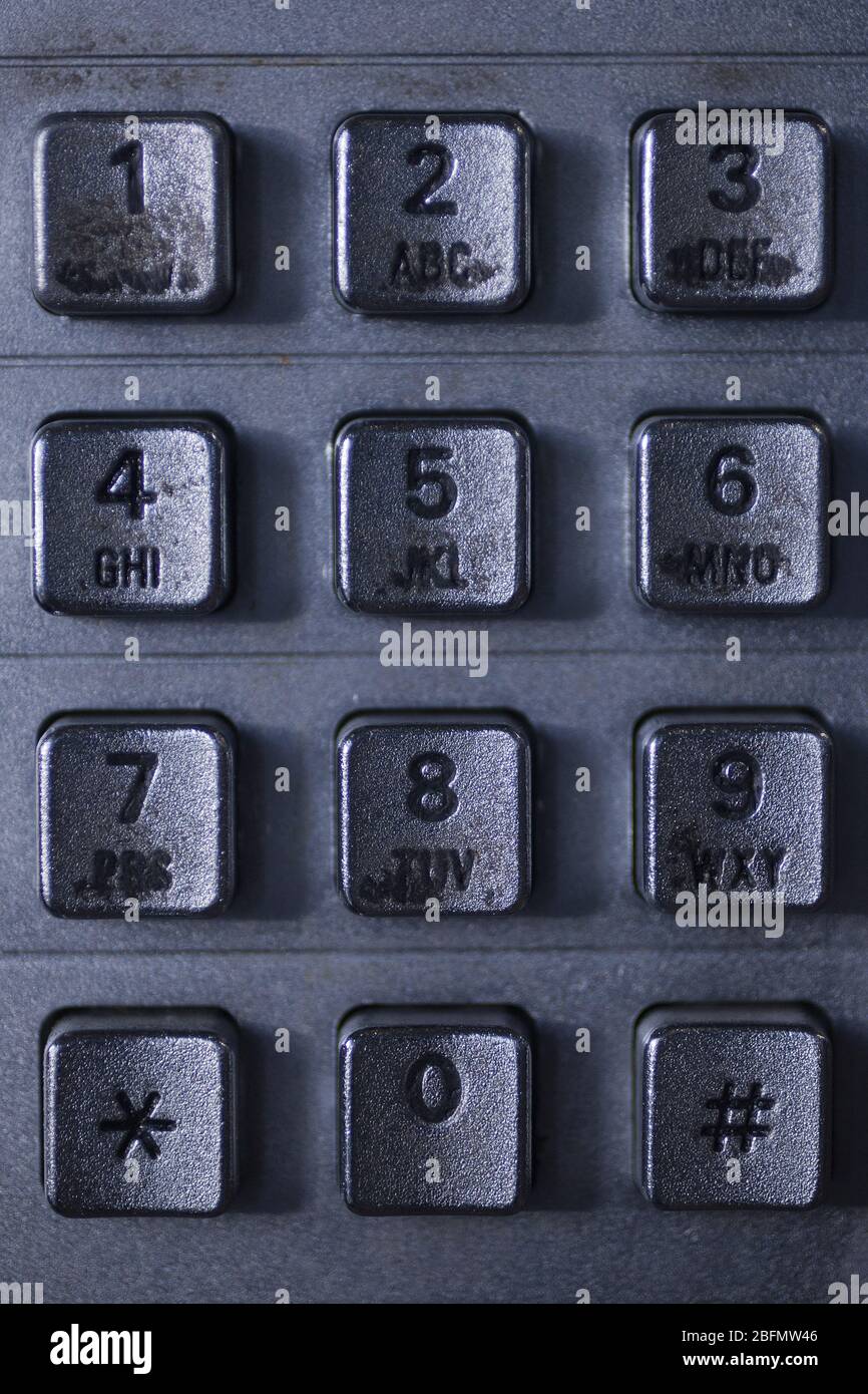 Primo piano di una tastiera metallica sporca per telefono pubblico. Visualizzazione macro dei pulsanti e delle cifre di un tastierino telefonico pubblico. Foto Stock