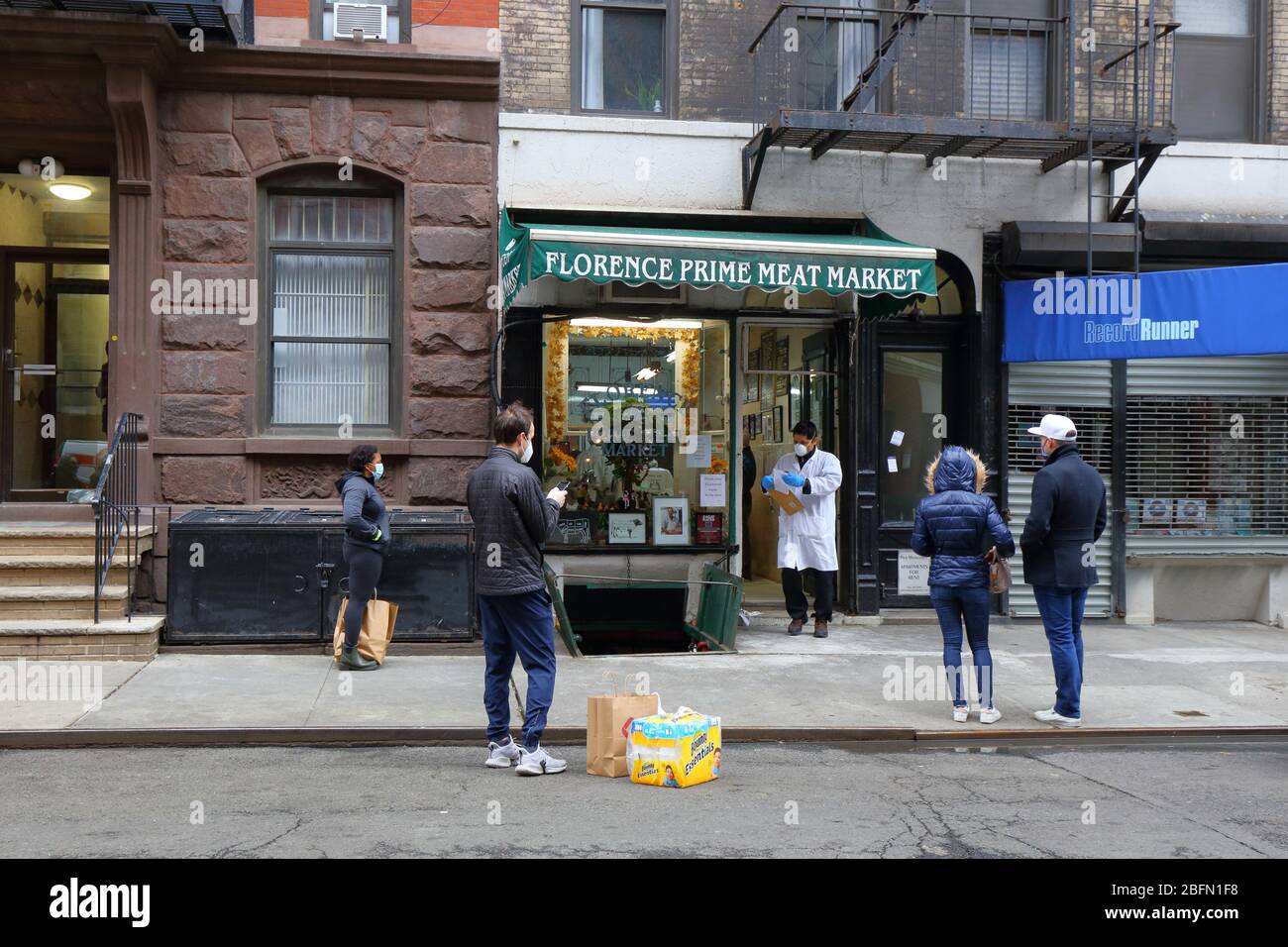 Persone sociali che si distanziano e indossano maschere come si aspettano per entrare in un macelleria durante coronavirus COVID-19. New York, 18 aprile 2020. Foto Stock