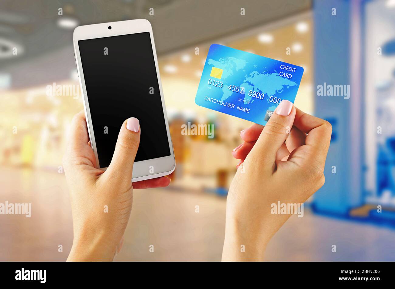 Le mani femminili mostrano lo smartphone mobile e la carta di credito, sfondo sfocato Foto Stock