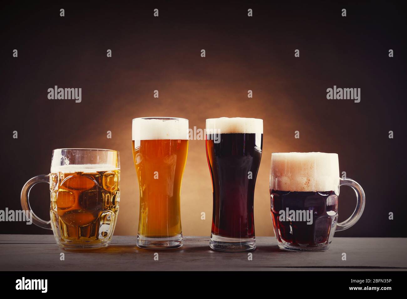 Diversi tipi di birra alla spina in bicchieri su tavolo di legno. Stilizzazione retrò Foto Stock