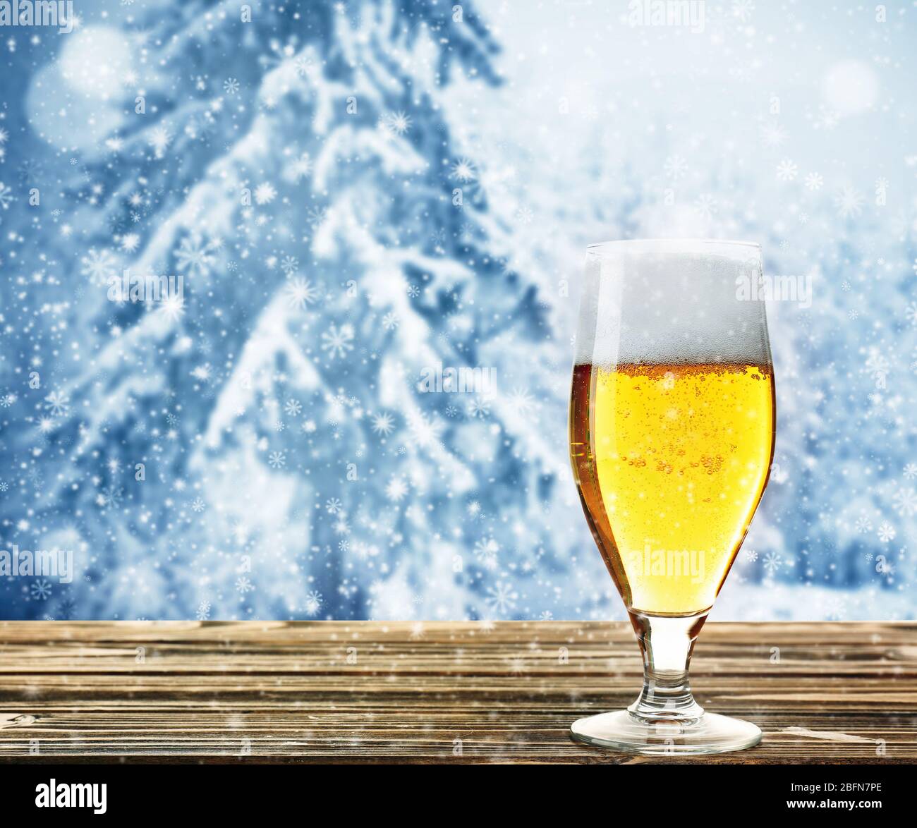 Bicchiere di birra su tavolo di legno contro sfondo invernale. Foto Stock