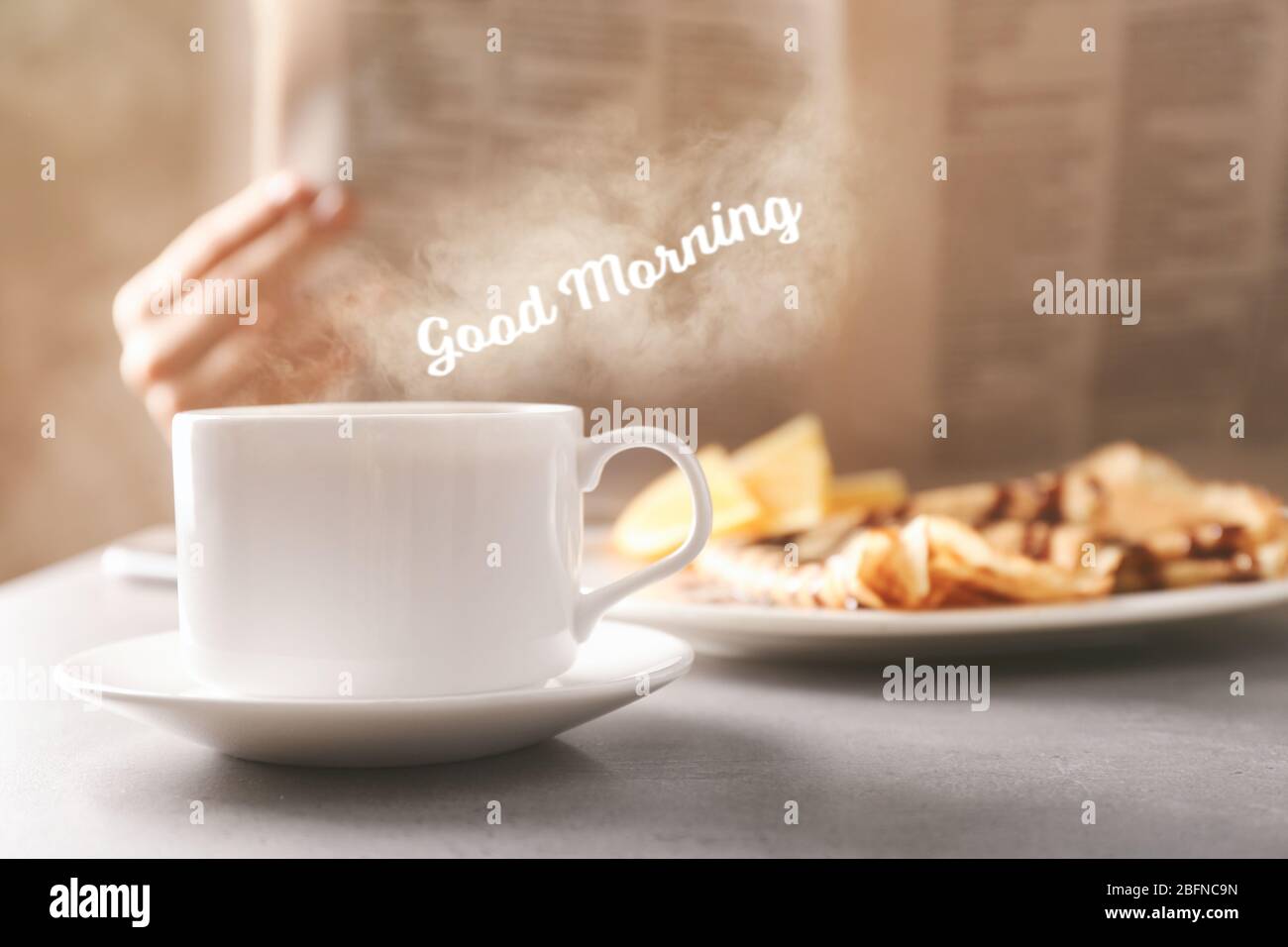 Tazza di bevanda aromatica sul tavolo. Testo BUONGIORNO sullo sfondo Foto Stock