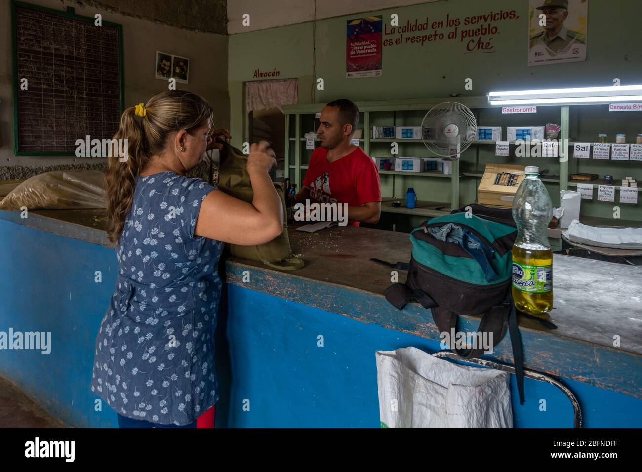 Donna che acquista cibo in un negozio di razione con un libro russo (razione libro) Salvador Cisneros, Viñales, Cuba Foto Stock