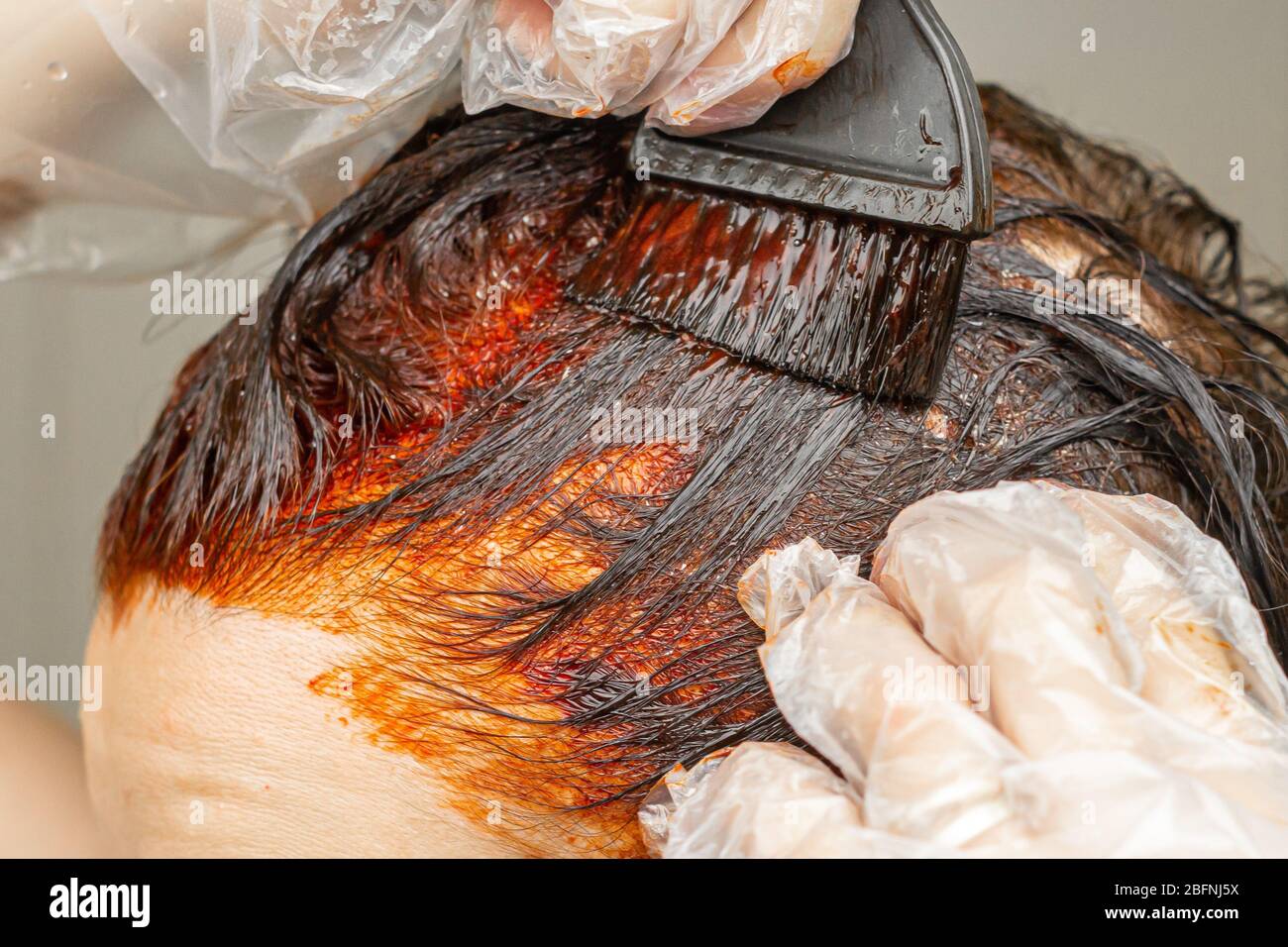 Tintura dei capelli in rosso a casa. Giovane donna sta colorando i suoi capelli. Foto Stock