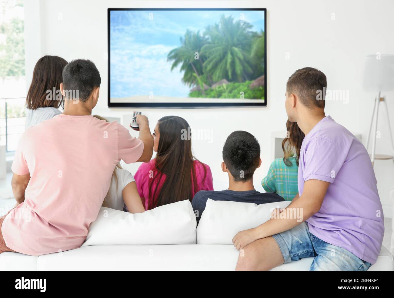 Gli amici guardano la TV in un accogliente soggiorno Foto Stock