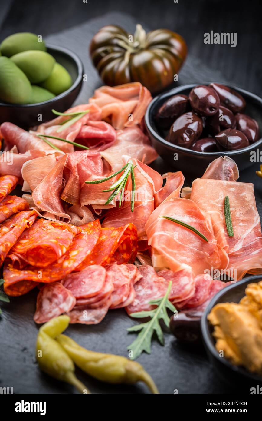 Piatto di antipasti con un misto di salame, prosciutto, chorizo, peperoni, pomodori e olive Foto Stock