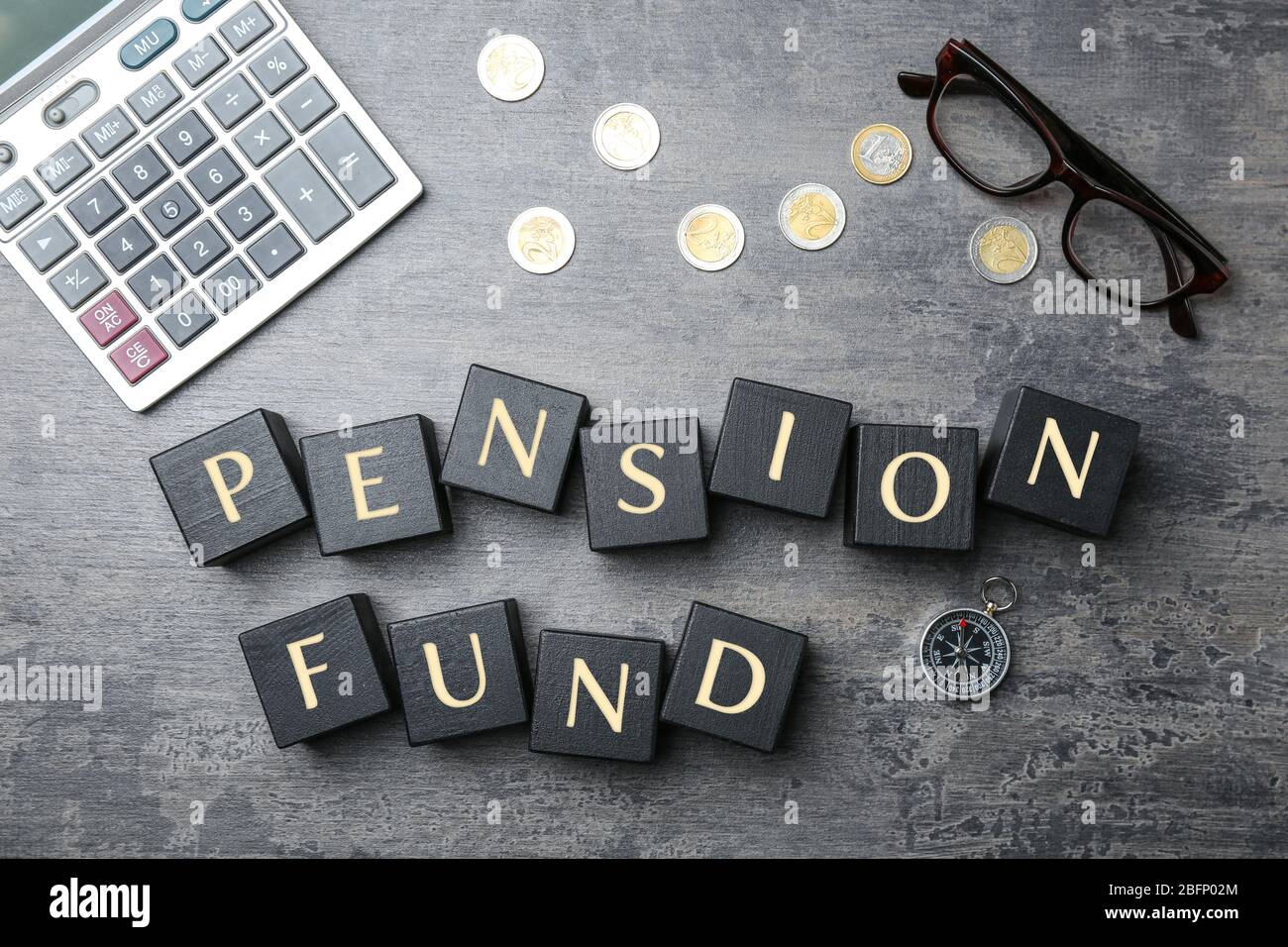 Cubi con testo FONDO PENSIONI, monete e calcolatrice su sfondo grigio Foto Stock
