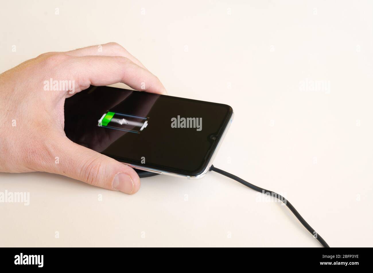 Un uomo ha preso lo smartphone dopo la ricarica dal caricabatterie a induzione wireless Foto Stock