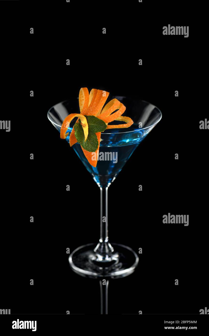 Decorazione per un cocktail di arancia e menta. Presentazione elegante e originale. Martini Blue Curacao su sfondo nero Foto Stock