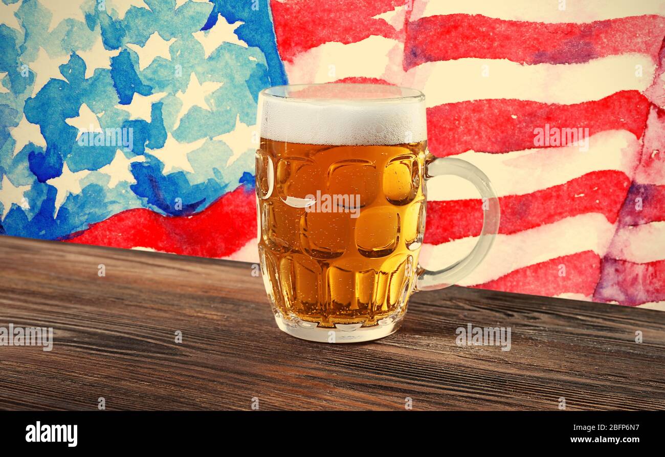 Bicchiere di birra su tavolo di legno. Sfondo bandiera USA. Foto Stock