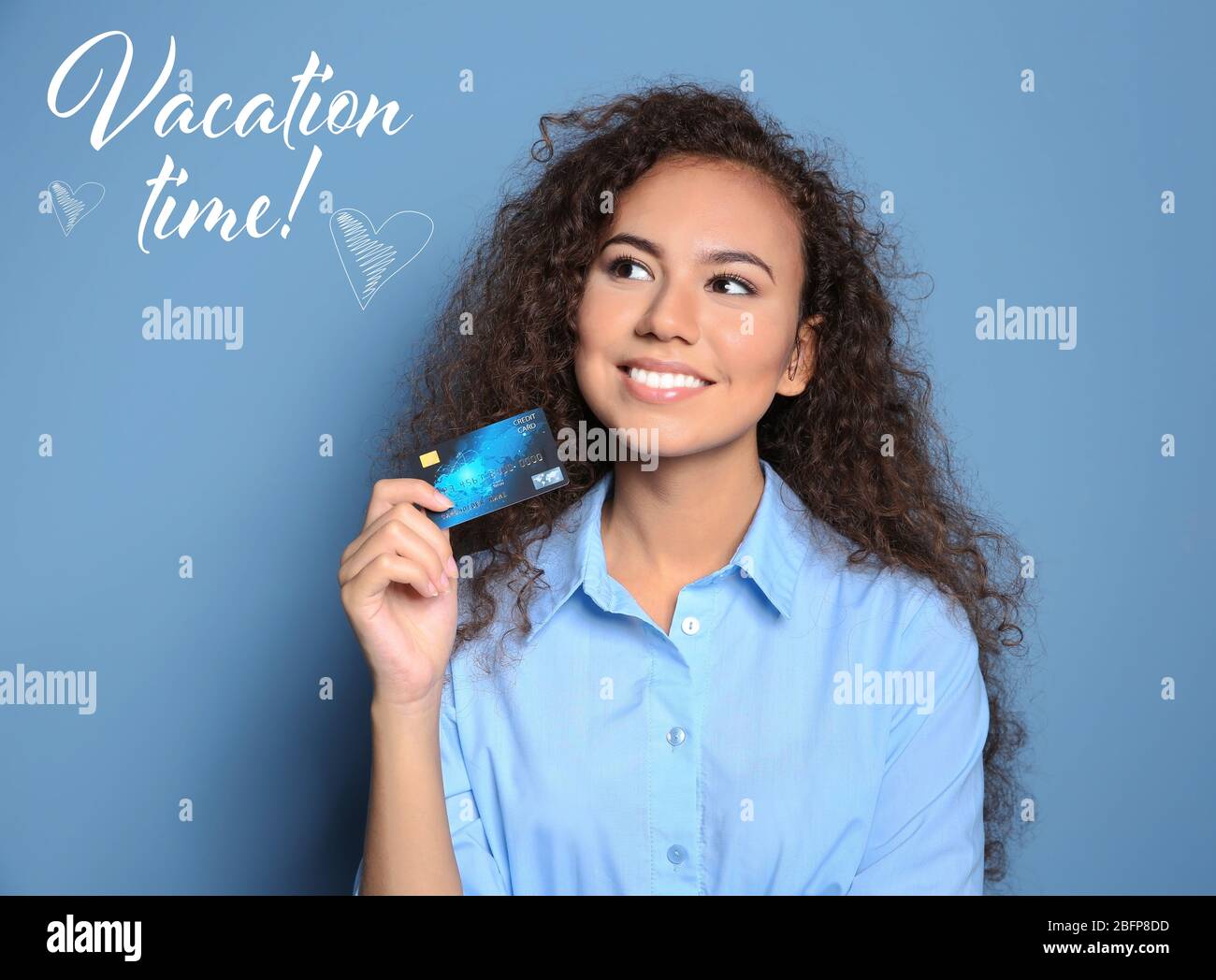 Concetto di tempo di vacanza. Donna attraente che tiene carta di credito su sfondo blu Foto Stock