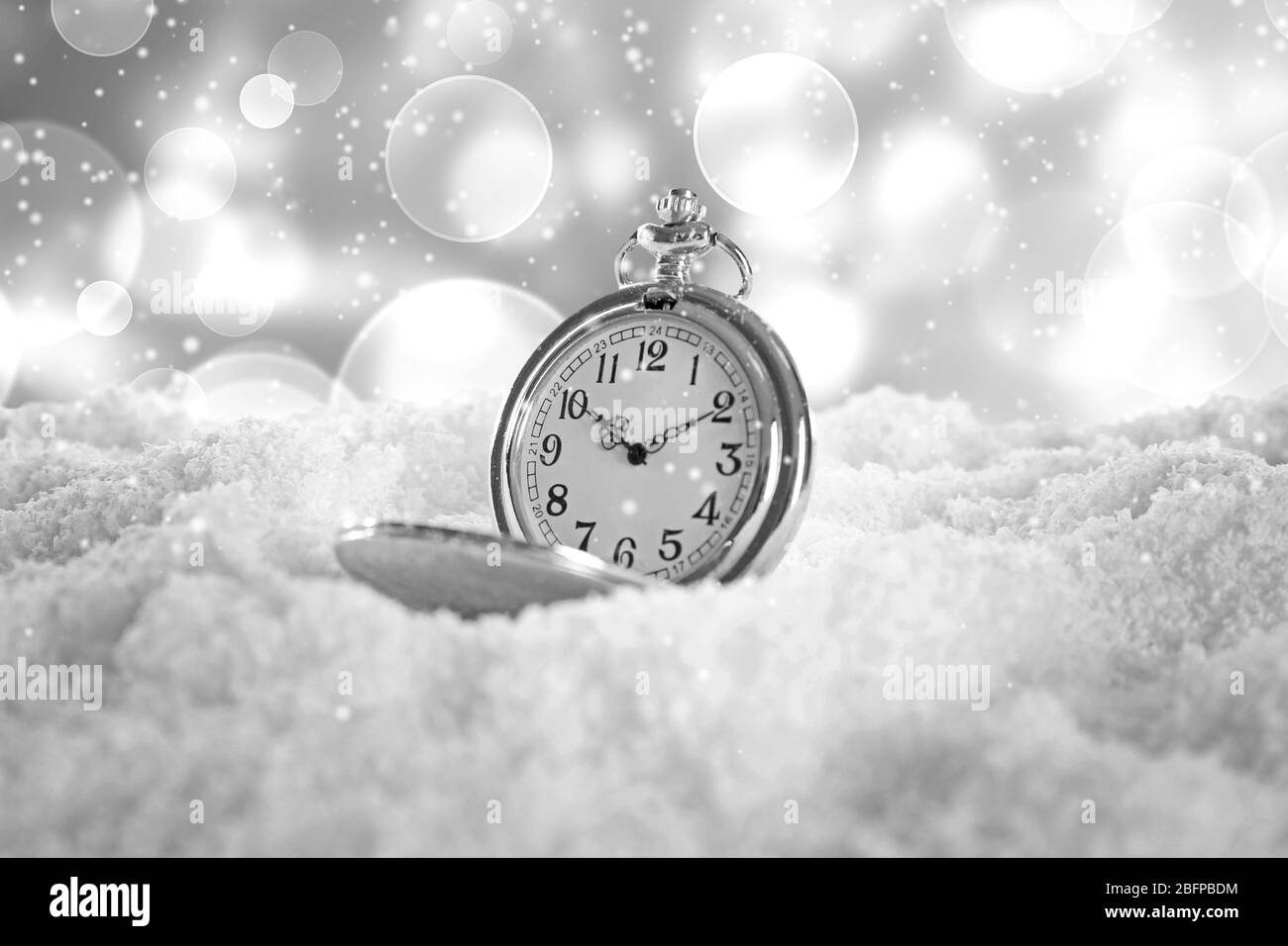 Orologio vintage tascabile sulla neve su sfondo sfocato. Concetto di Natale. Foto Stock
