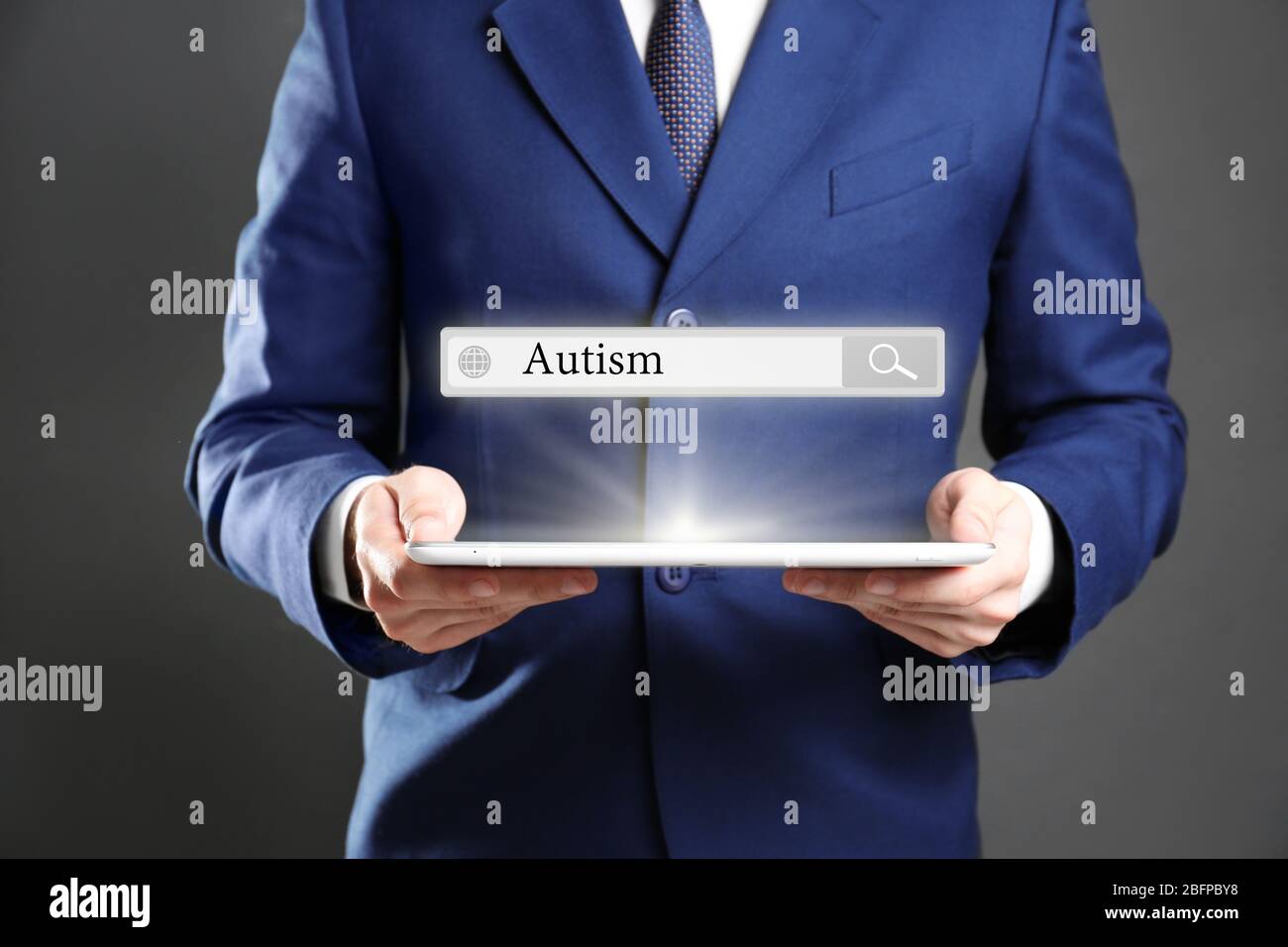 Uomo d'affari con tablet su sfondo grigio. Concetto di autismo per bambini Foto Stock