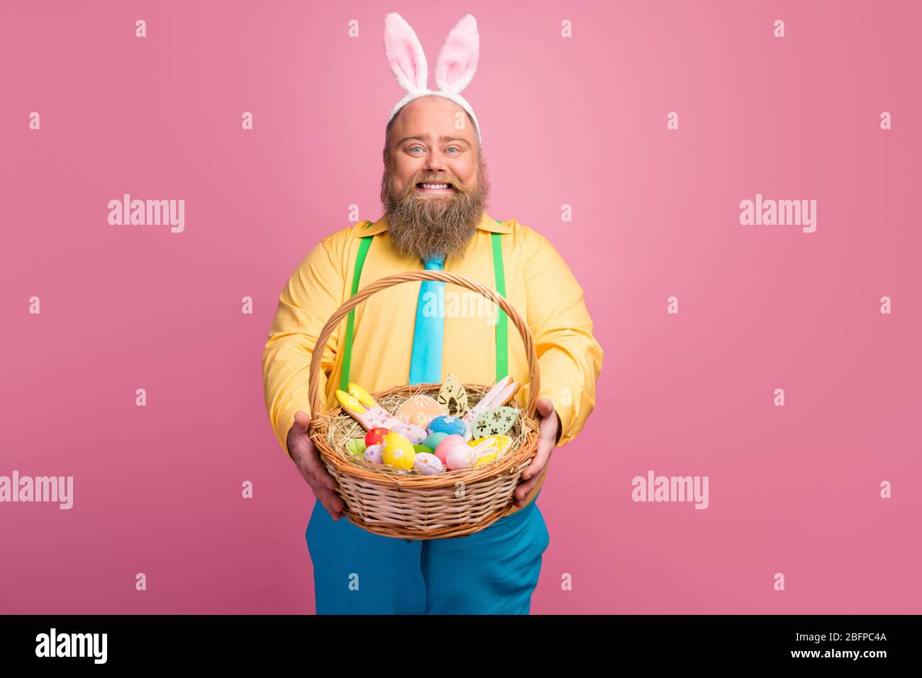 Ritratto del suo simpatico amichevole funky felice ragazzo bearded dandogli festal cesto pasquale fatto a mano congratulandosi isolato su pastello rosa Foto Stock