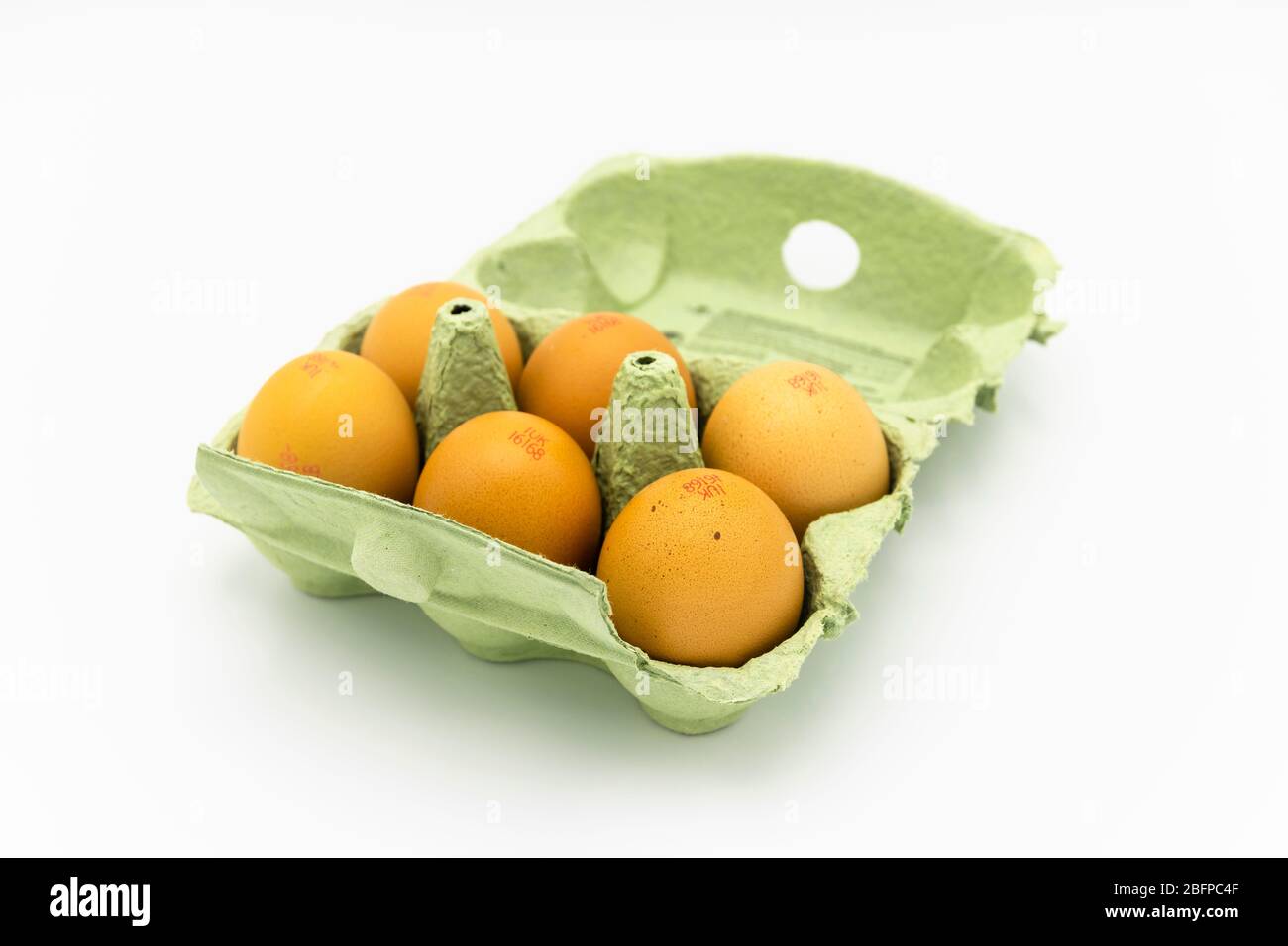 Eggbox di cartone verde, completamente aperto, contenente mezza dozzina di uova di gallina fresche marroni speckled dal Regno Unito, su uno sfondo bianco Foto Stock