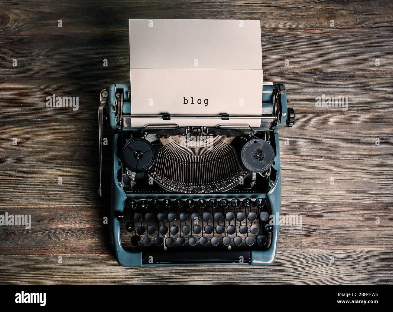 Foglio di carta con blog di parola in macchina da scrivere su sfondo di legno Foto Stock