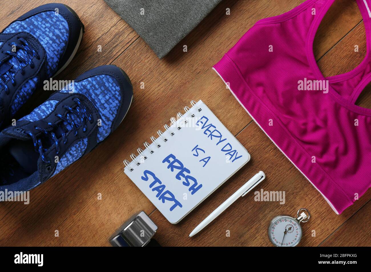 Preventivi fitness. Il testo OGNI GIORNO È UN INIZIO FRESCO in notebook e sport su sfondo di legno Foto Stock
