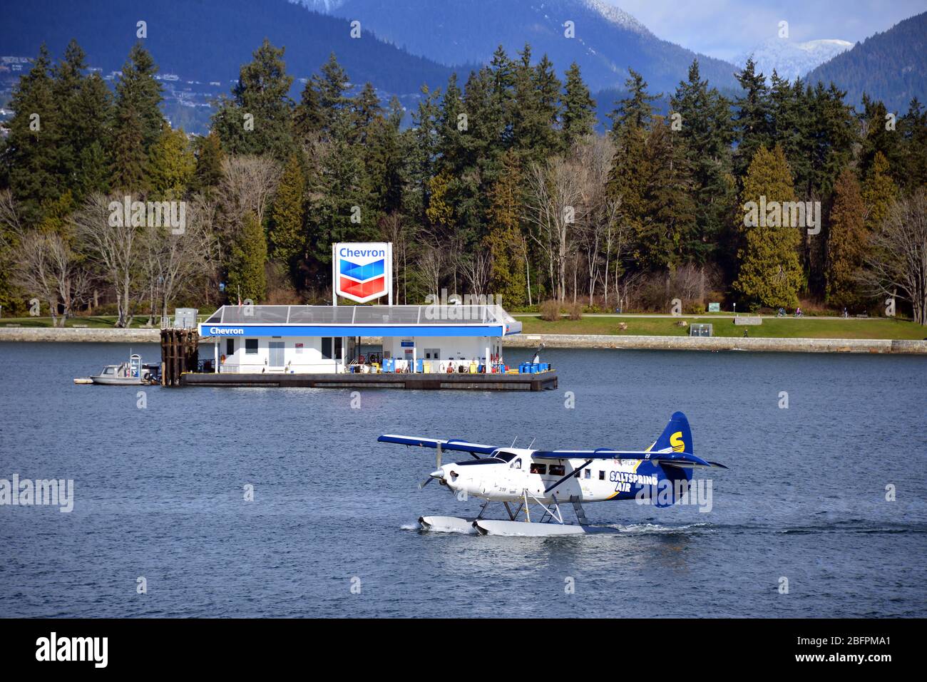 Vancouver, Canada - 4 marzo 2020: Un aereo marittimo Salt Spring Air atterra nel porto di Vancouver. La chiatta di carburante marina Chevron è sullo sfondo. Foto Stock