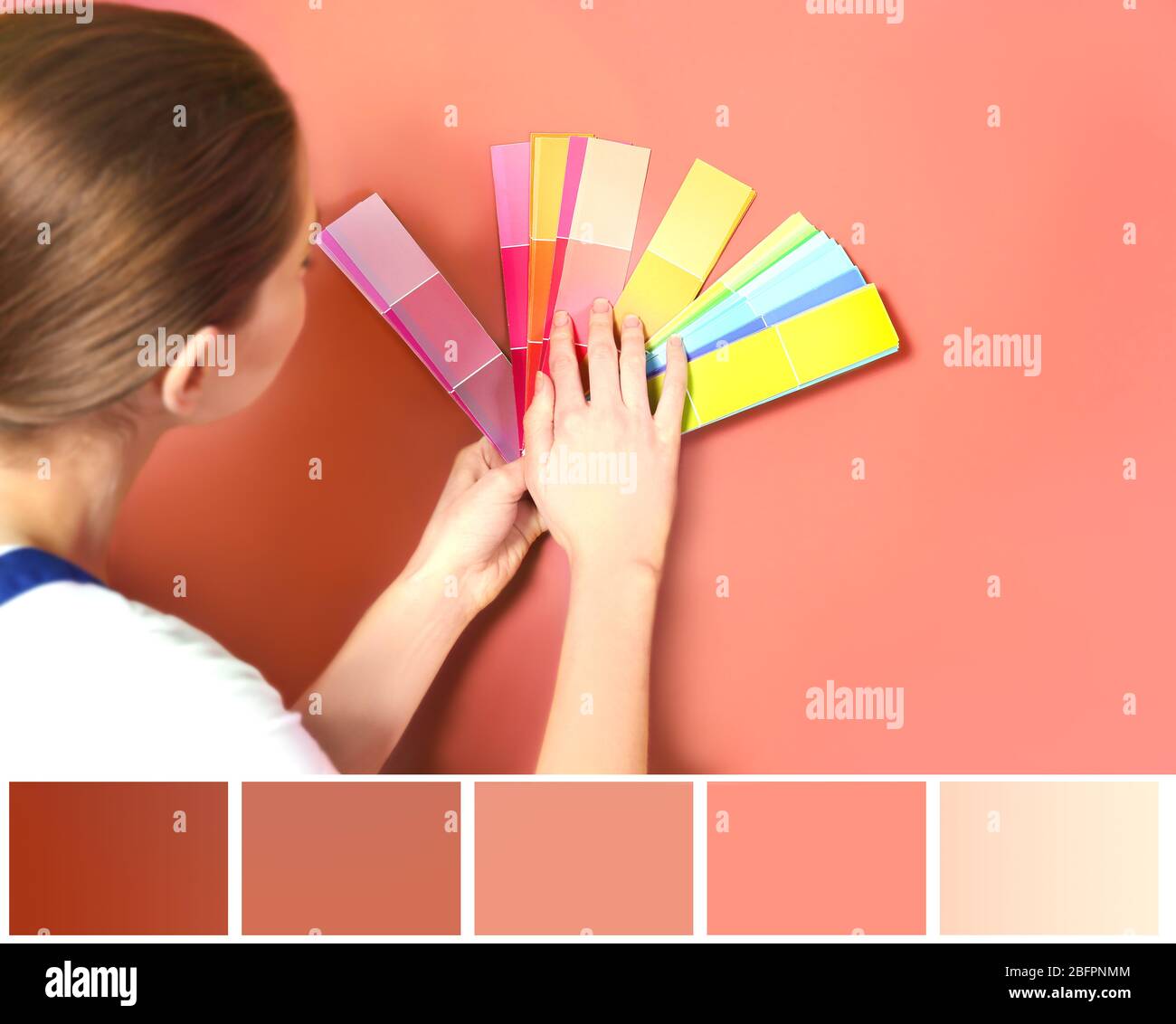 Tavolozza con colore salmone e giovane decoratore che seleziona il tono della parete Foto Stock
