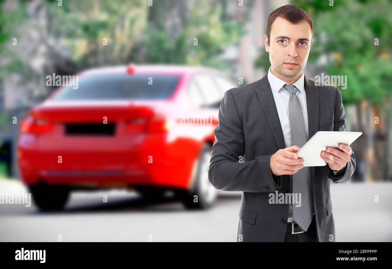 Agente assicurativo che utilizza tablet e auto in background Foto Stock