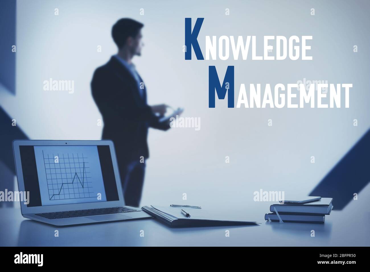 Concetto di gestione della conoscenza. Luogo di lavoro con notebook e uomo in background Foto Stock