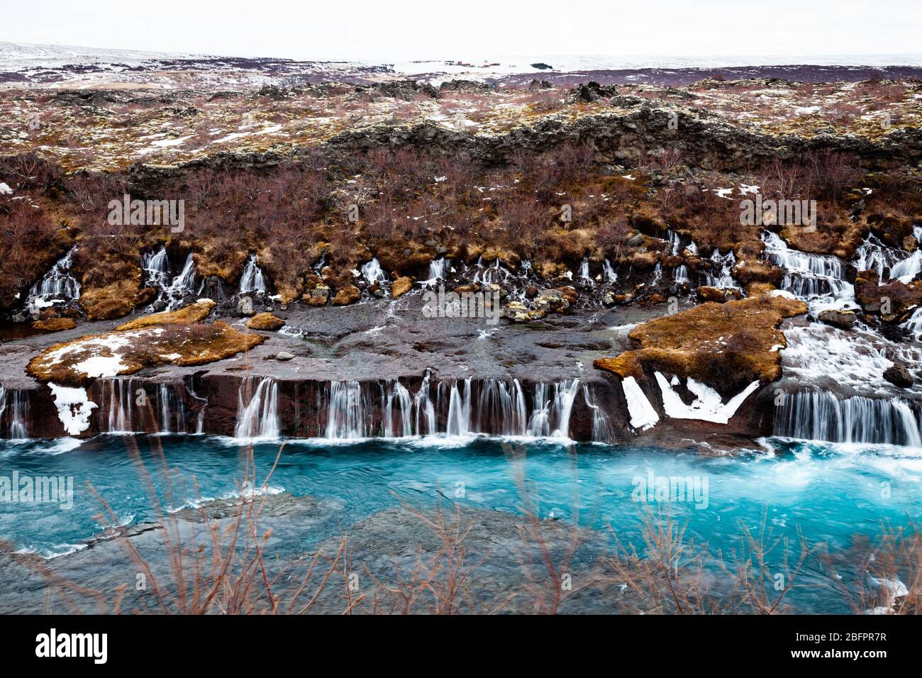 Cascate di Hraunfossar che si innaldissero nel fiume Hvita alimentato dai ghiacciai in Islanda in inverno Foto Stock
