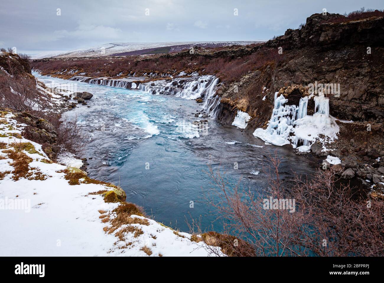 Il fiume Hvita, alimentato dal ghiacciaio, in Islanda in inverno con le cascate di Hraunfossar Foto Stock