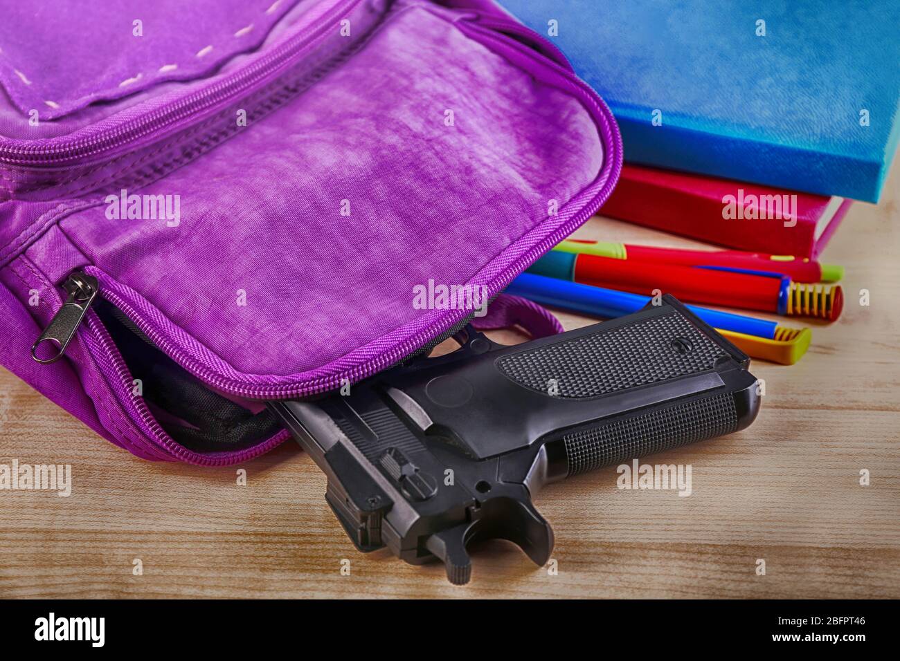 Zaino con pistola sul tavolo, primo piano. Concetto di ripresa della scuola Foto Stock