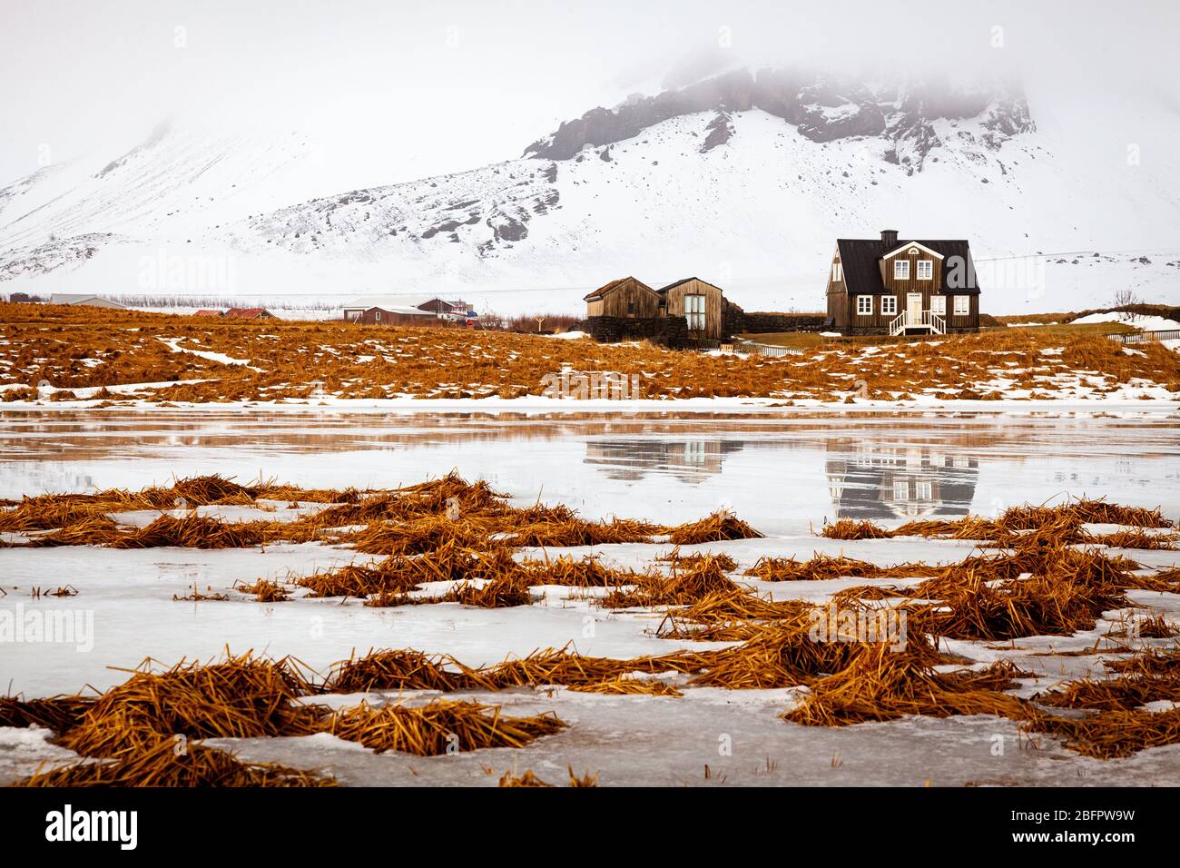 Casa Amtmannshusid ad Arnarstapi sulla penisola di Snaefellsnes in Islanda in una giornata invernale ghiacciata e nevosa nei toni dell'arancio e del bianco Foto Stock