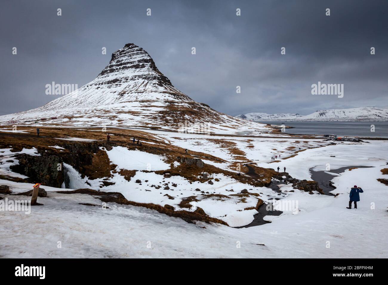 Montagna di Kirkjufell coperta di neve con i turisti nel paesaggio innevato, Grundarfjordur, Penisola di Snaefellsnes, Islanda Foto Stock