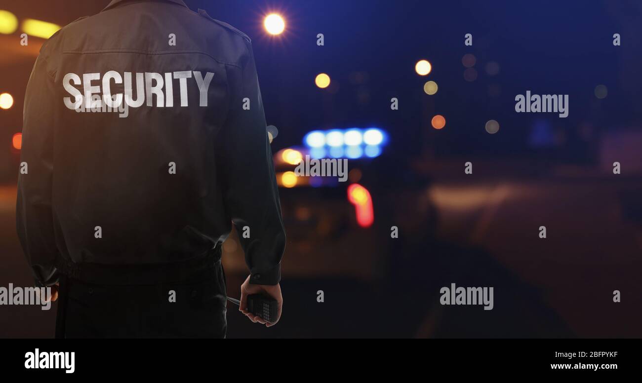 Guardia di sicurezza vicino all'auto all'aperto di notte Foto Stock