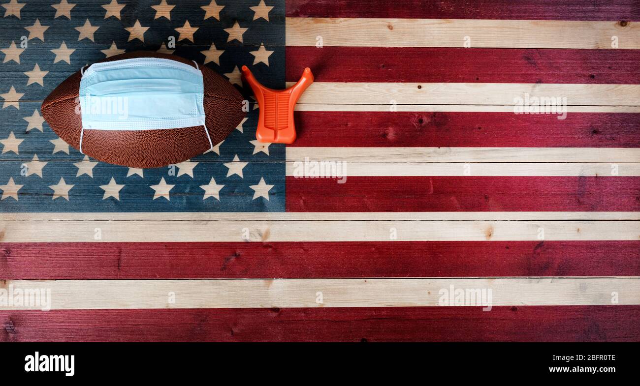 Calcio americano con maschera chirurgica protettiva e tee calciante su sfondo vintage della bandiera degli Stati Uniti d'America. Concetto di coronavirus per la footba influenza Foto Stock