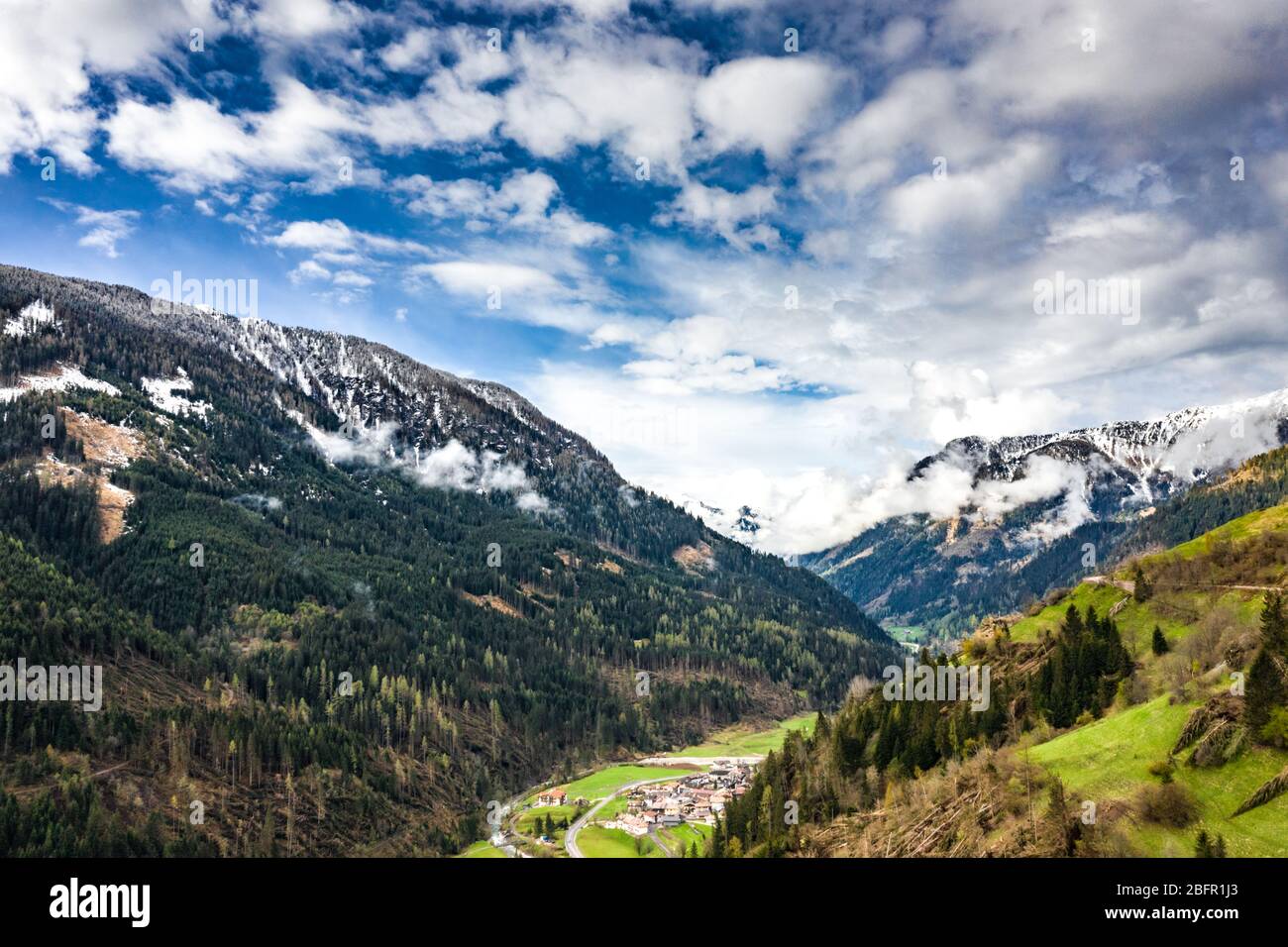 Veduta aerea della valle con verdi pendici delle montagne d'Italia, il Trentino, gli alberi caduti dal vento, enormi nuvole su una valle, verde Foto Stock