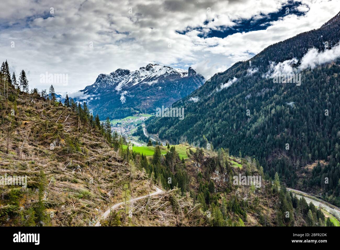 Veduta aerea della valle con verdi pendici delle montagne d'Italia, il Trentino, gli alberi caduti dal vento, enormi nuvole su una valle, verde Foto Stock