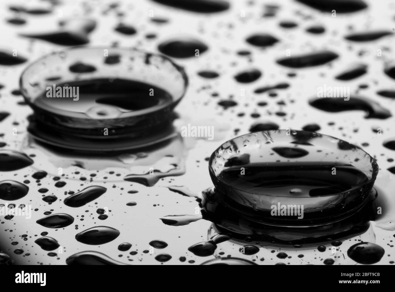 lente a contatto con gocce su sfondo grigio Foto Stock