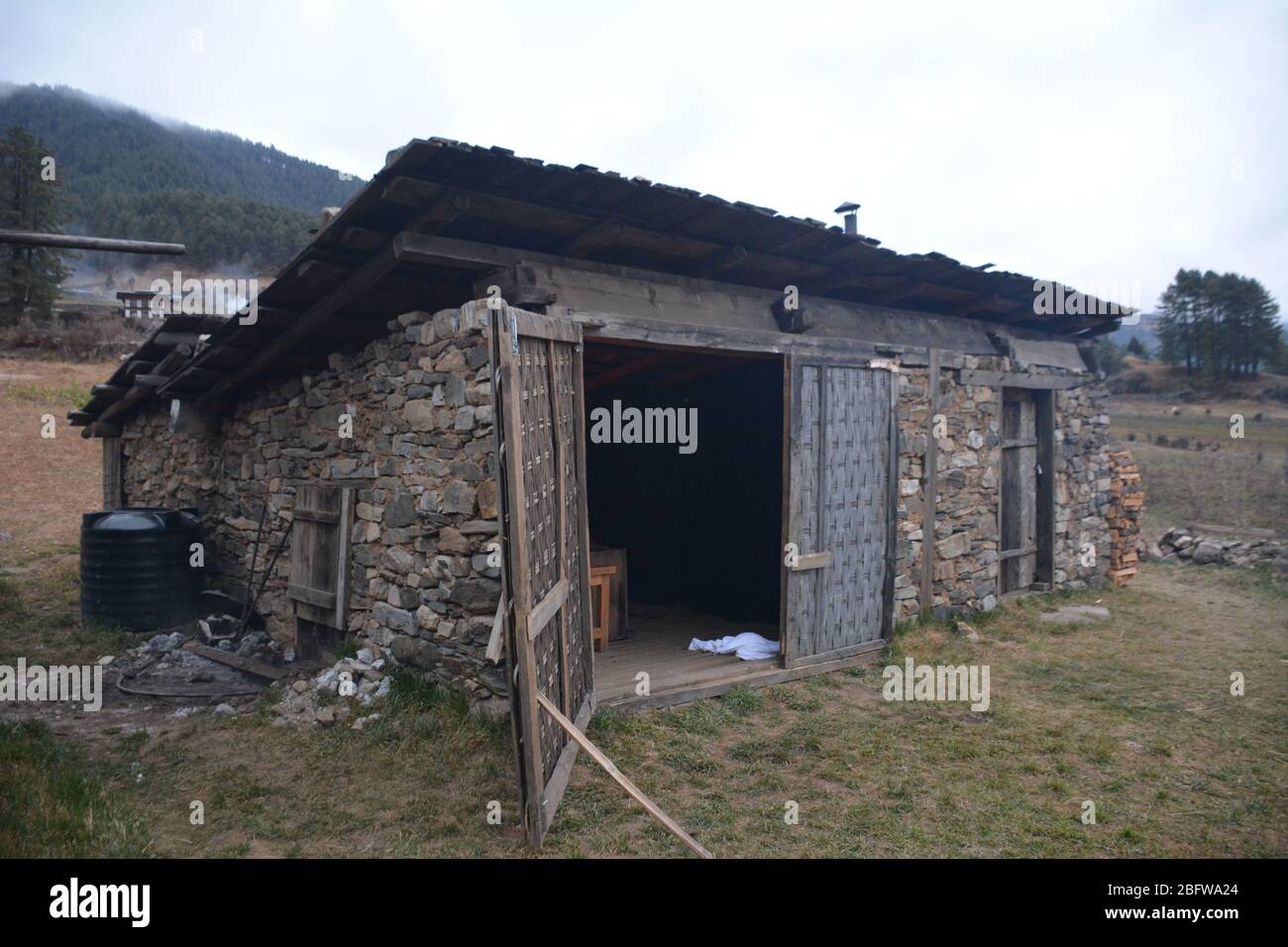 Un bagno tradizionale in pietra calda completo di un fuoco da campeggio e vista della valle di Phobjika, Bhutan. Foto Stock