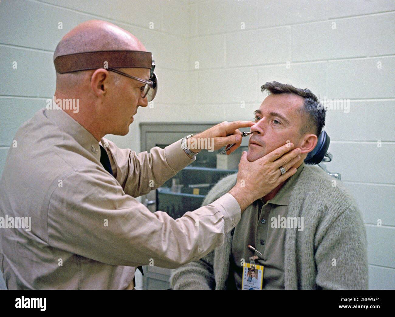 Astronauta John W. Young, pilota per la Gemini-Titan missione 3, subisce un orecchio, naso e gola esame dal dottor L. Ballenberger Foto Stock