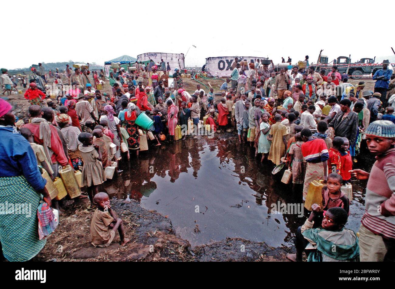 1994 Zaire- profughi dal Ruanda amaro della guerra civile tra le etnie hutu e tutsi tribù in Africa australe, raccogliere con qualcosa che possa tenere acqua, per ottenere tanto bisogno di cibo e acqua, fornito da militari Usa i soccorsi. Foto Stock