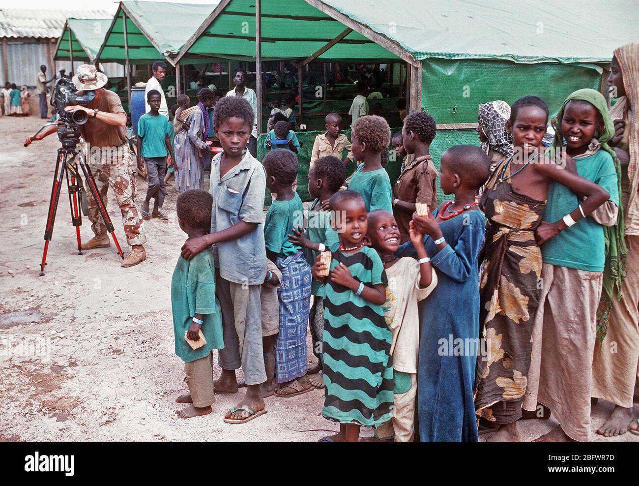 1993 - capo fotografo il compagno di Robert Sasek videotape somali allineando per un pasto presso la preoccupazione del centro di alimentazione durante la multinazionale soccorsi RESTORE HOPE. Il centro è gestito dagli irlandesi in rilievo la preoccupazione dell'organizzazione. Foto Stock