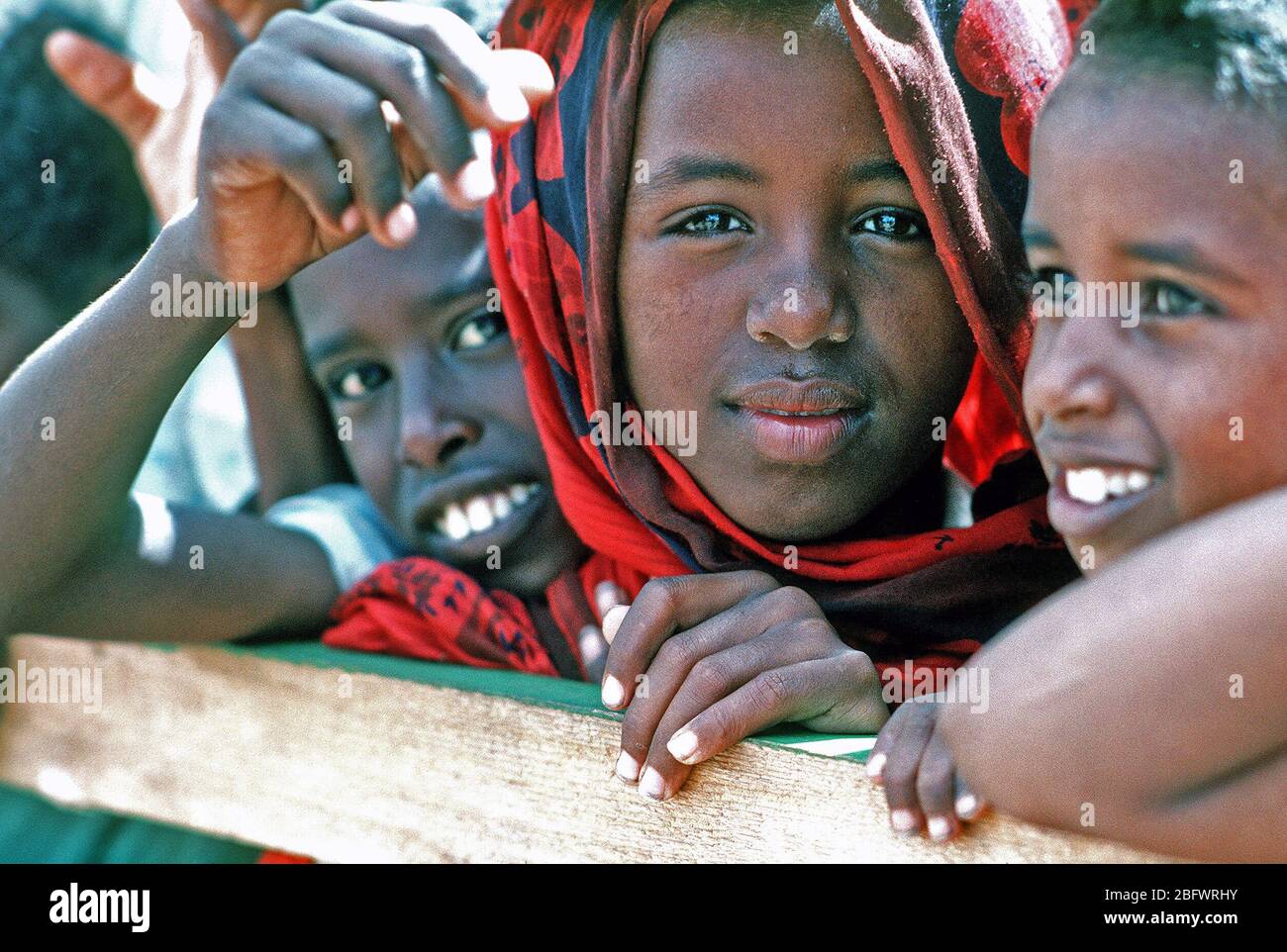 1993 - somalo bambini guardare i membri del Naval Mobile Battaglione di costruzione 1 (NMCB-1) come lavorano per migliorare una scuola locale durante la multinazionale soccorsi RESTORE HOPE. Foto Stock