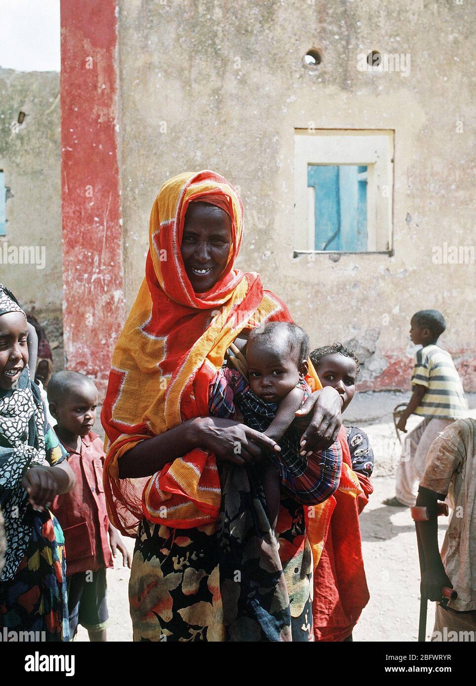 1993 - Una donna somala pone con alcuni bambini durante la multinazionale soccorsi Restore Hope. Foto Stock