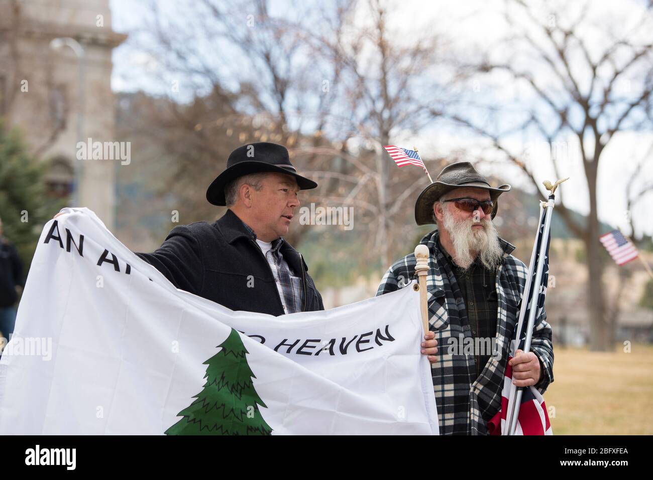 Helena, Montana - 19 aprile 2020: Due uomini si trovano di fronte al palazzo del governo per protestare contro la riapertura dello stato a causa della chiusura del governo per C. Foto Stock