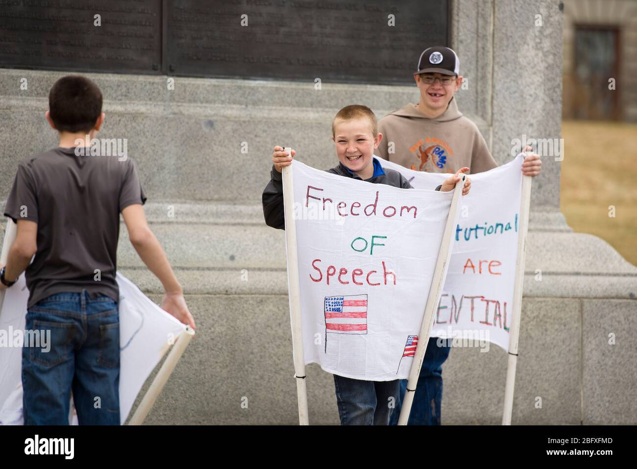Helena, Montana - 19 aprile 2020: Ragazzi bambini sorridono e ridono tenendo la libertà di espressione segni a una protesta al Campidoglio per il soggiorno a casa orde Foto Stock