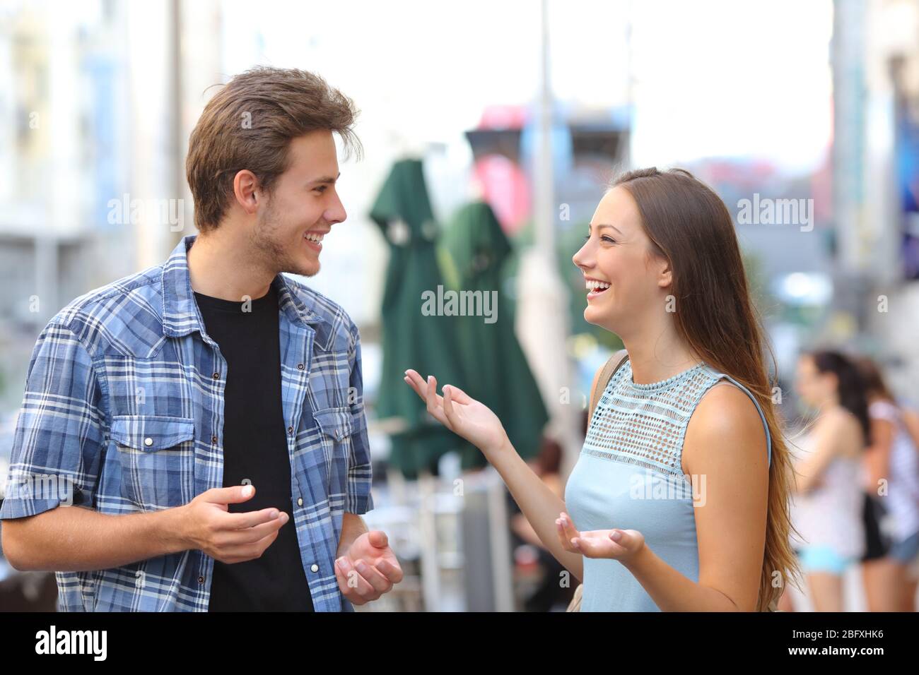 Due amici felici che si incontrano e parlano per strada in una città Foto Stock