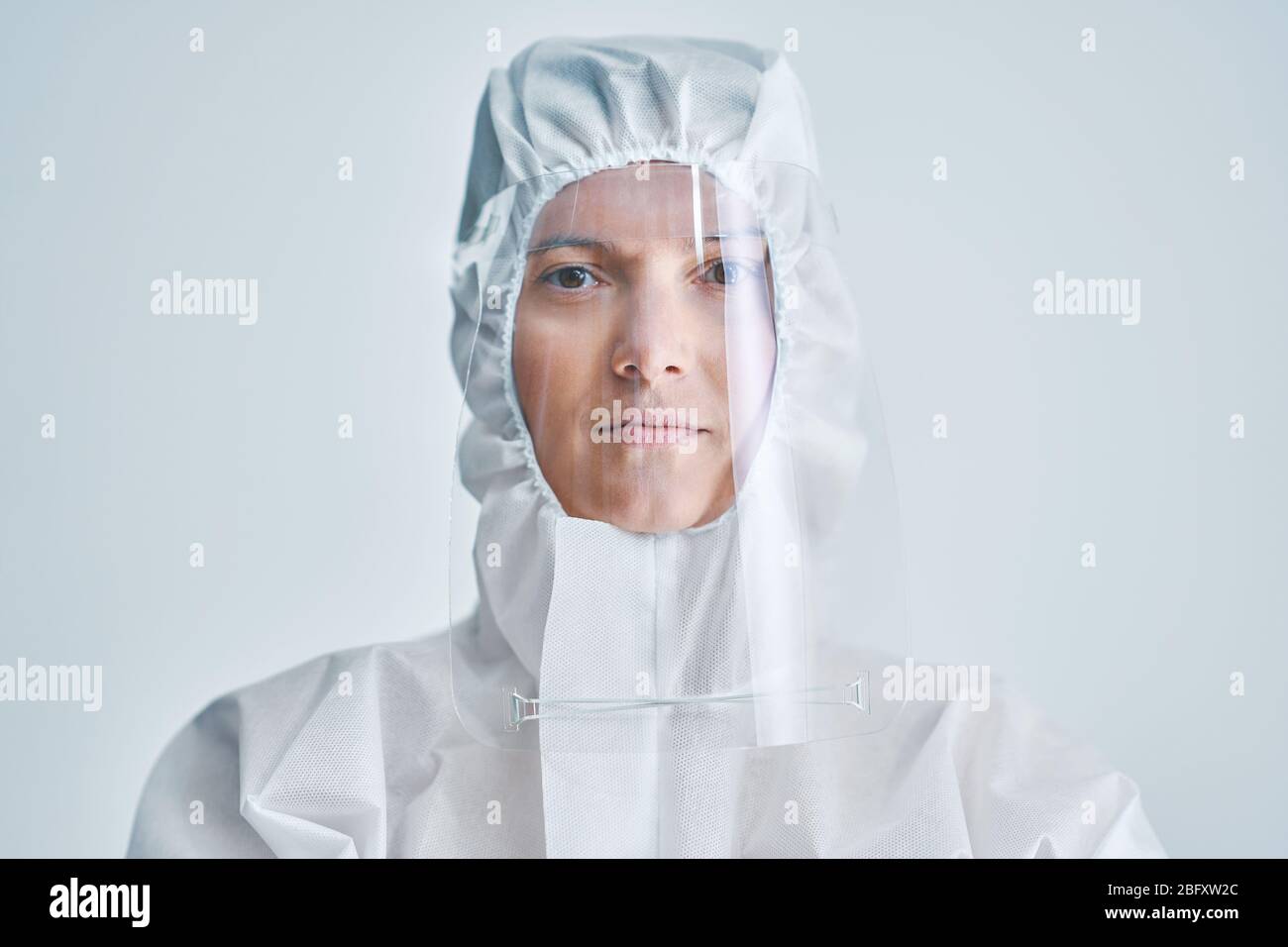 Donna in tuta a rischio biologico e visiera su sfondo bianco. Foto Stock