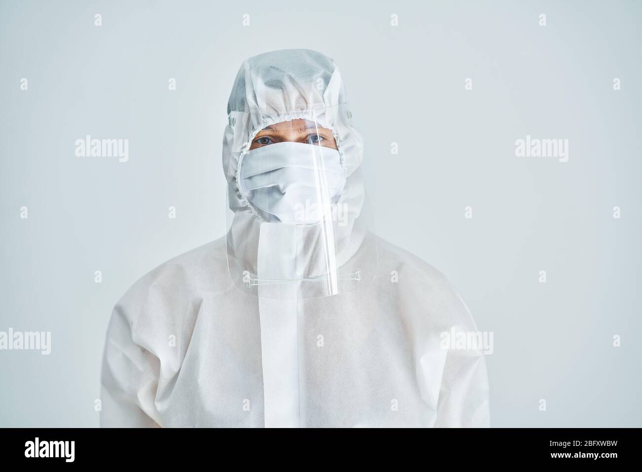 Donna in tuta a rischio biologico e visiera su sfondo bianco. Foto Stock